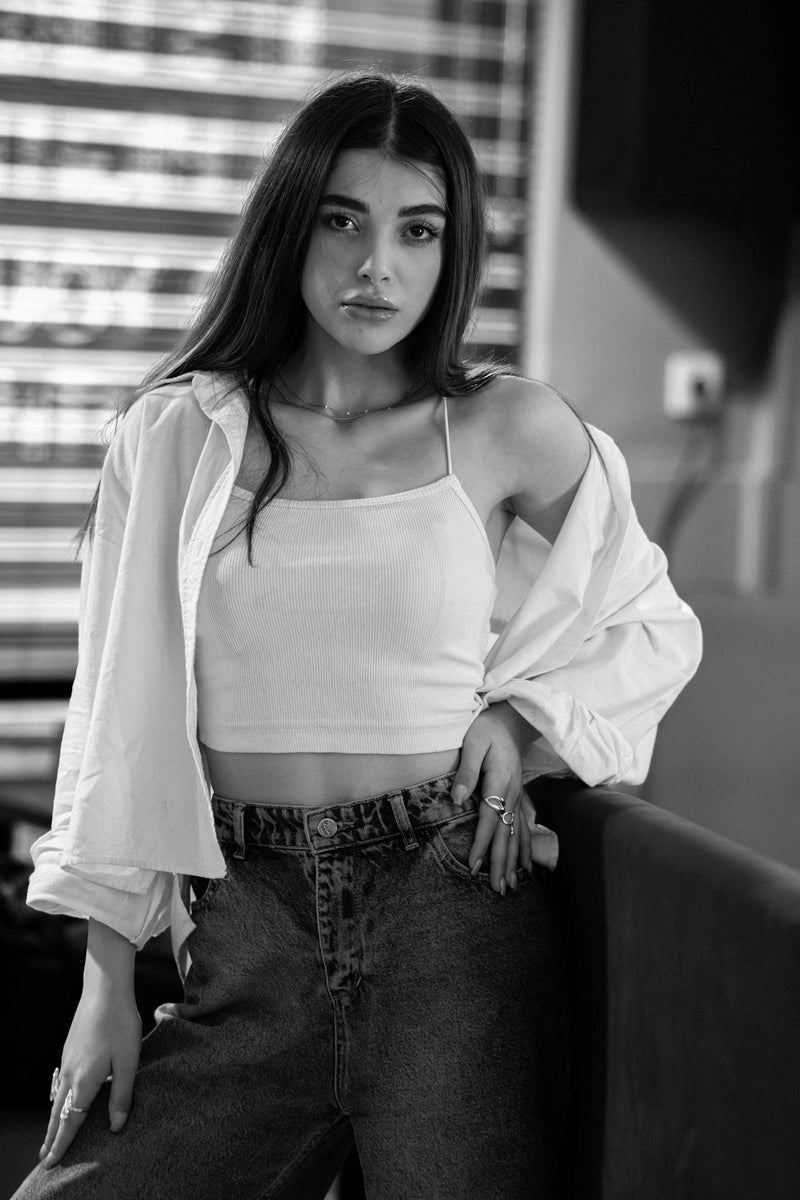 A young woman in casual clothes posing indoors.