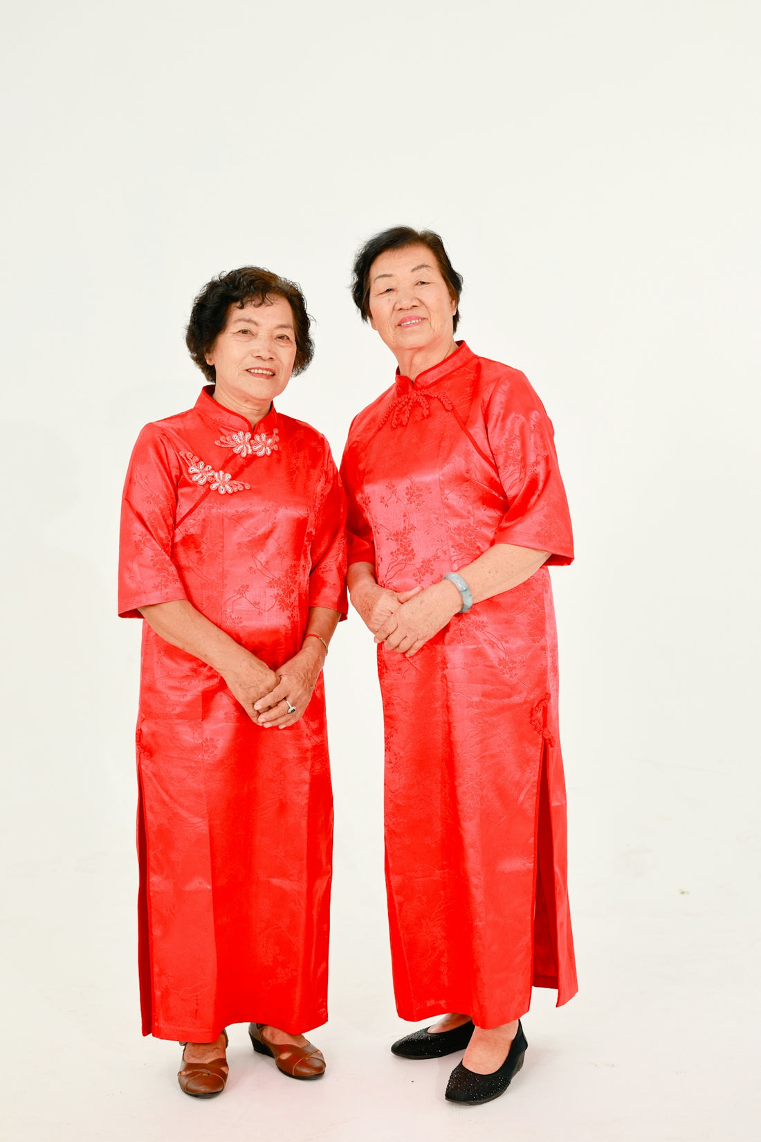Two elderly asian women in red traditional dresses.